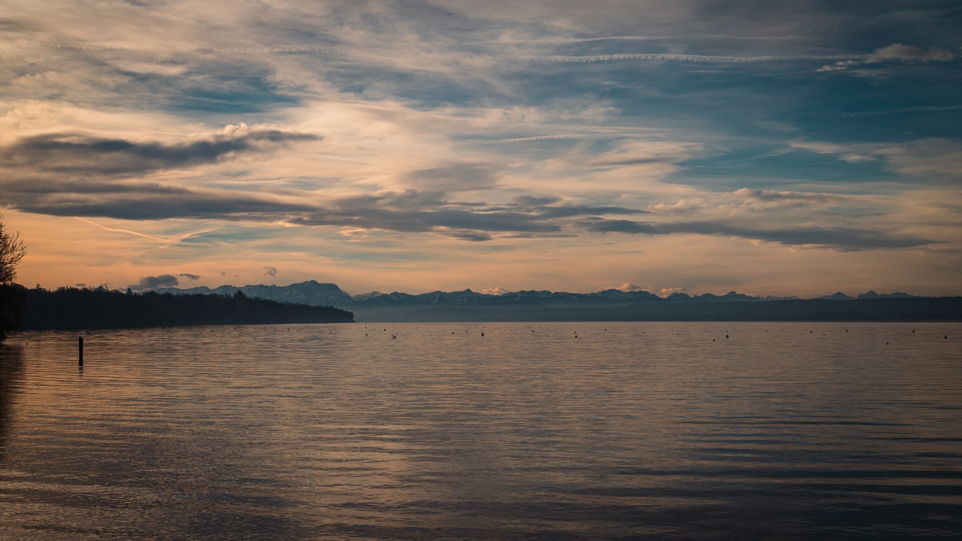 En stille sø i aftenlys under en skyet himmel